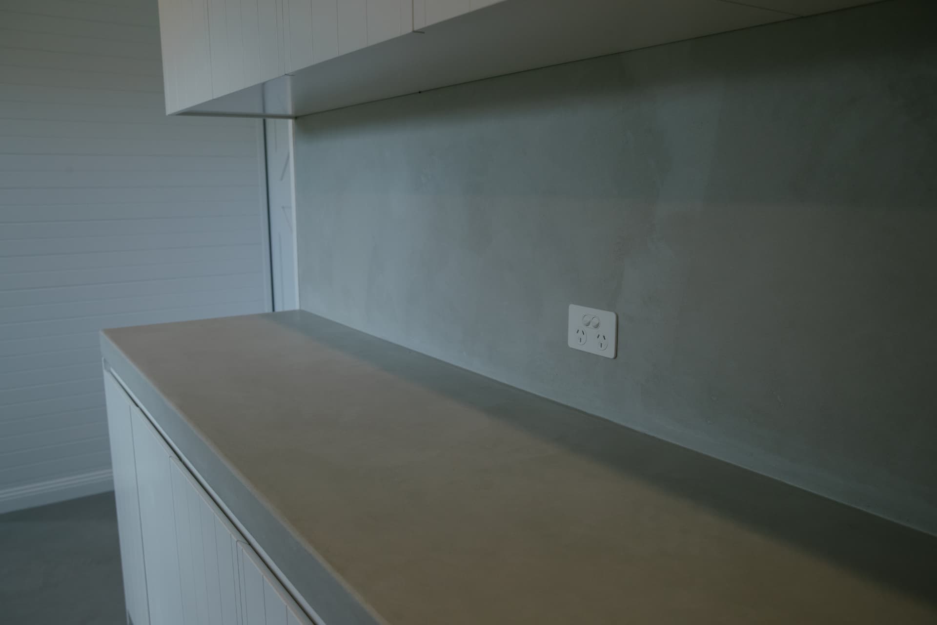 Cast concrete laundry benchtop with overhead cabinetry