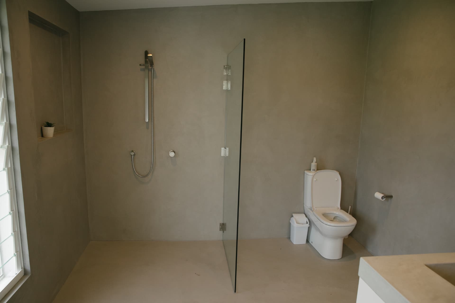 Myalup wet-room shower with a frameless glass screen and microcement walls