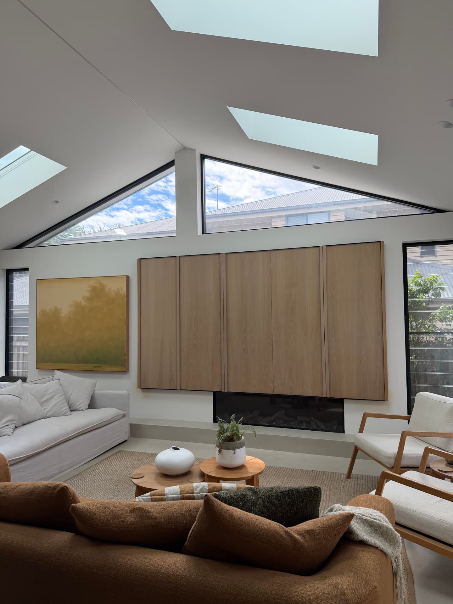 Living room with a raked ceiling, twin skylights and a full-height oak joinery wall