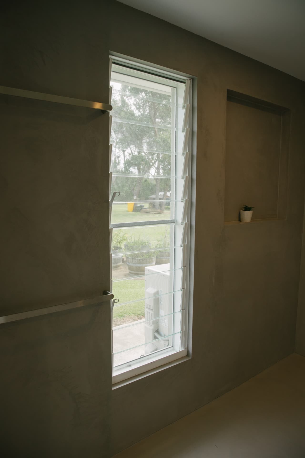 Louvre window set into a plaster reveal with stainless rails